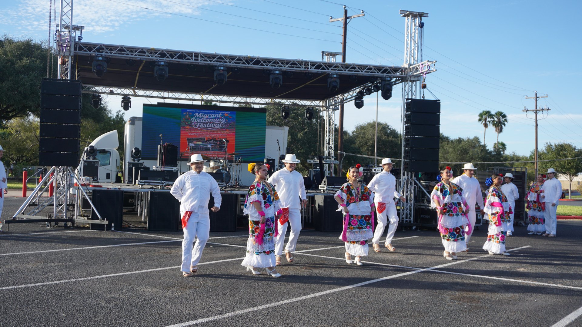Dance partners face one another in rows in front of the outdoor festival stage.
