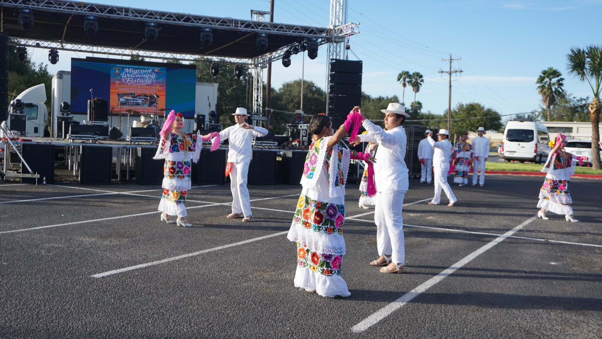 Couples extend their arms while dancing in front of the outdoor festival stage.
