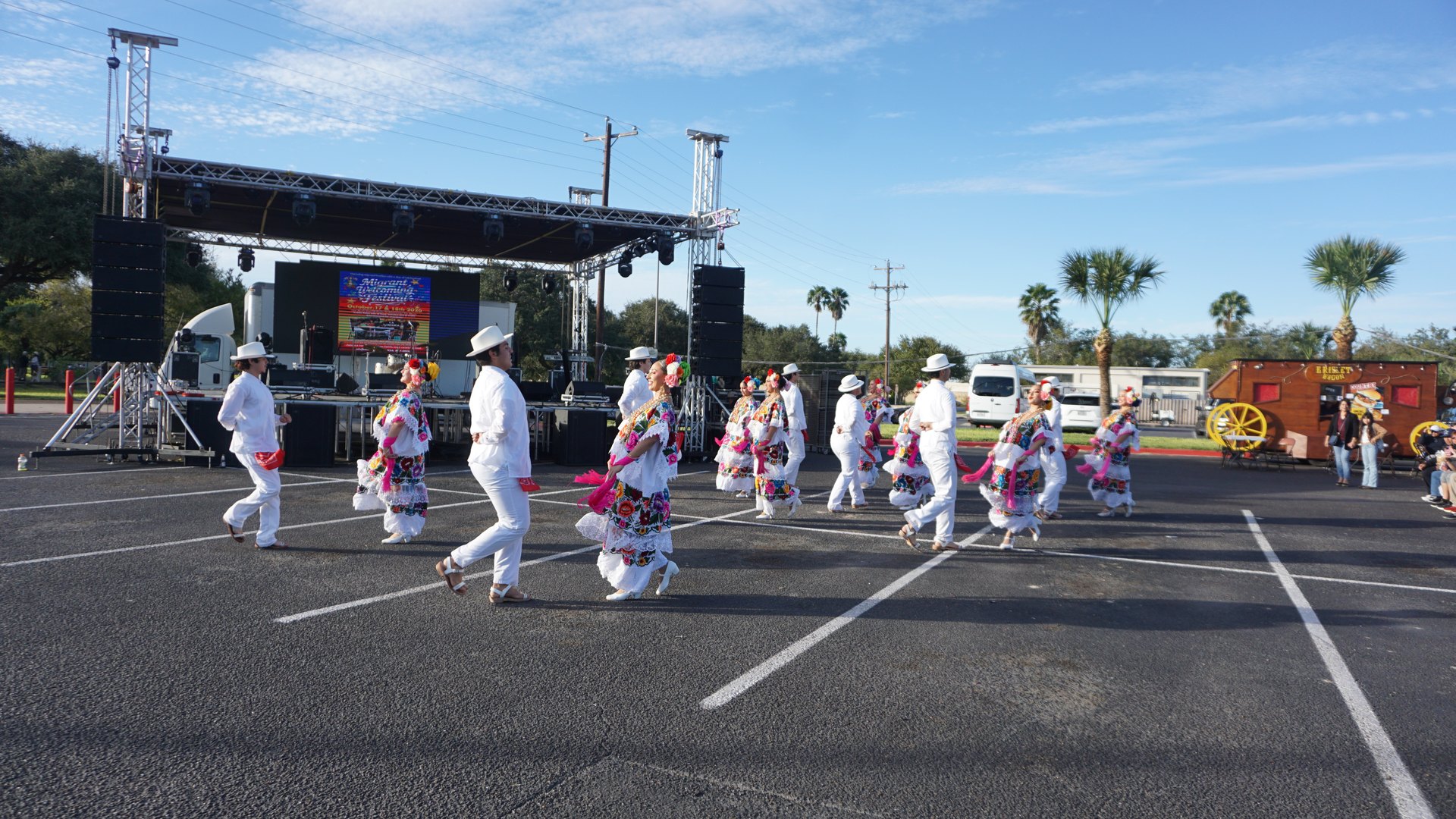 Dance partners move across the marked performance area in front of the festival stage.