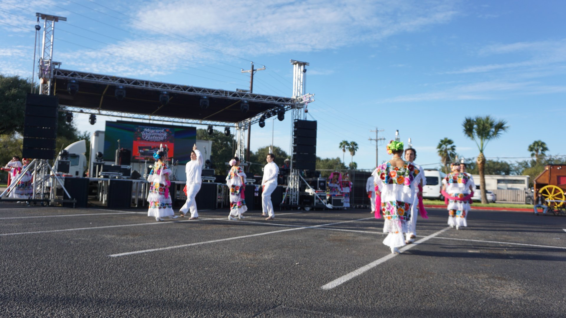 Wide view of dancers finishing a formation in the outdoor festival performance area.