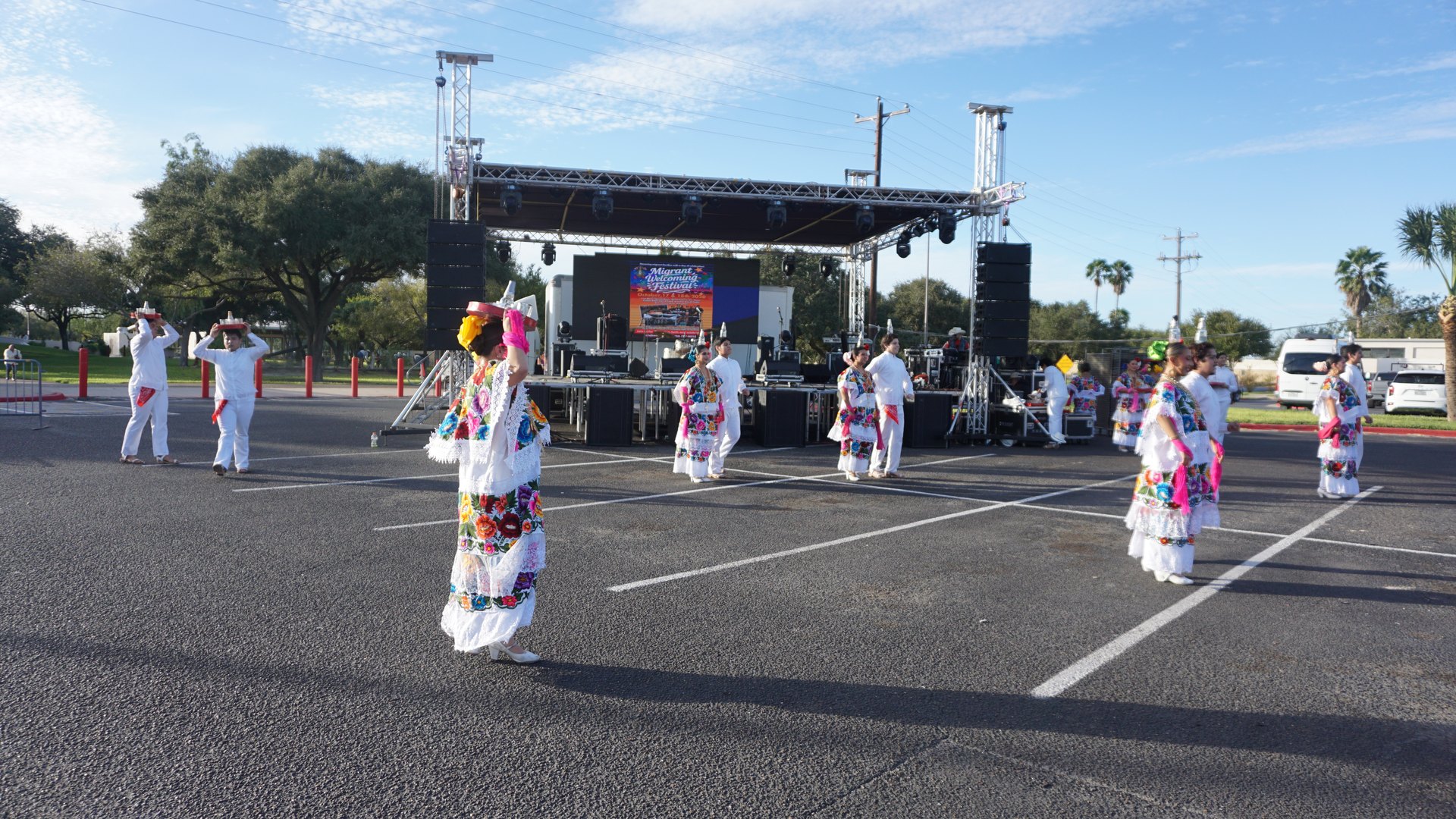 Dancers spread across the outdoor performance area with the festival stage behind them.