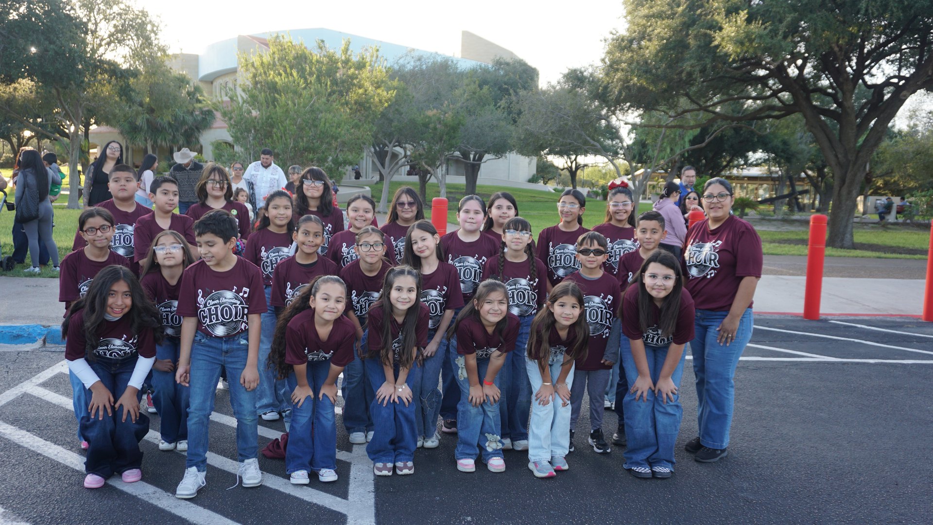 Children and adults in matching maroon choir shirts pose together outside the Basilica at the 2026 festival.