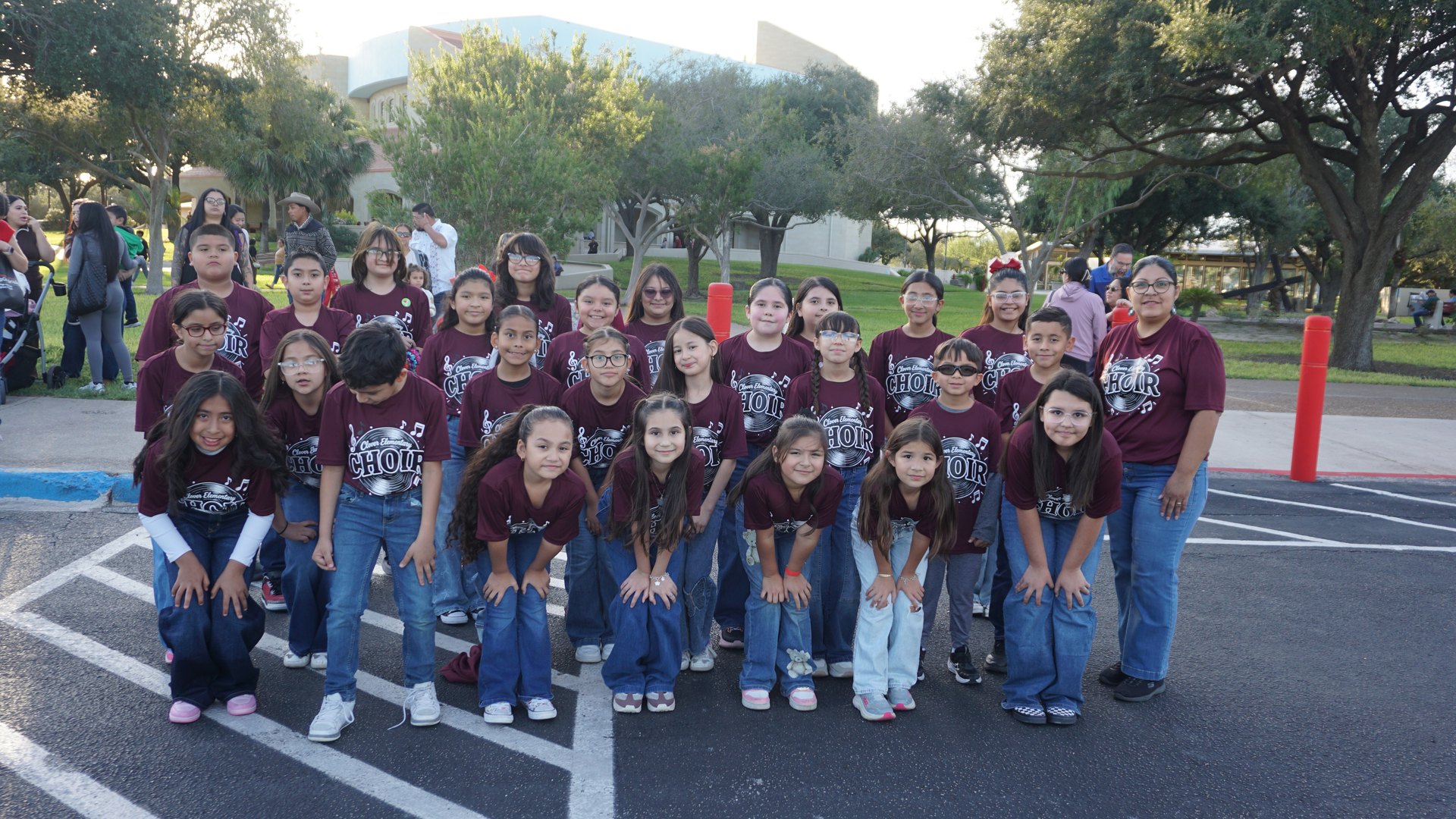 A choir group in maroon shirts poses in rows on the Basilica grounds at the 2026 festival.