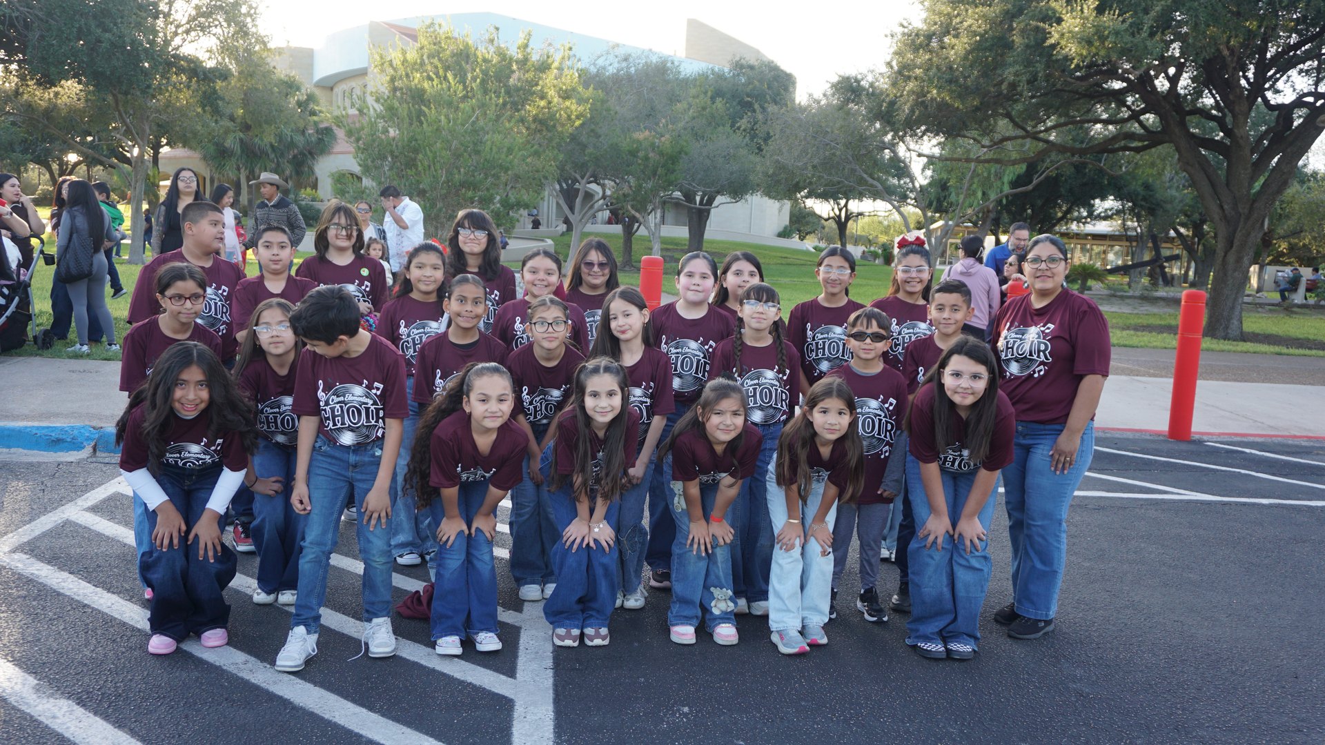 Choir members in matching maroon shirts gather for a group photo with the Basilica behind them.