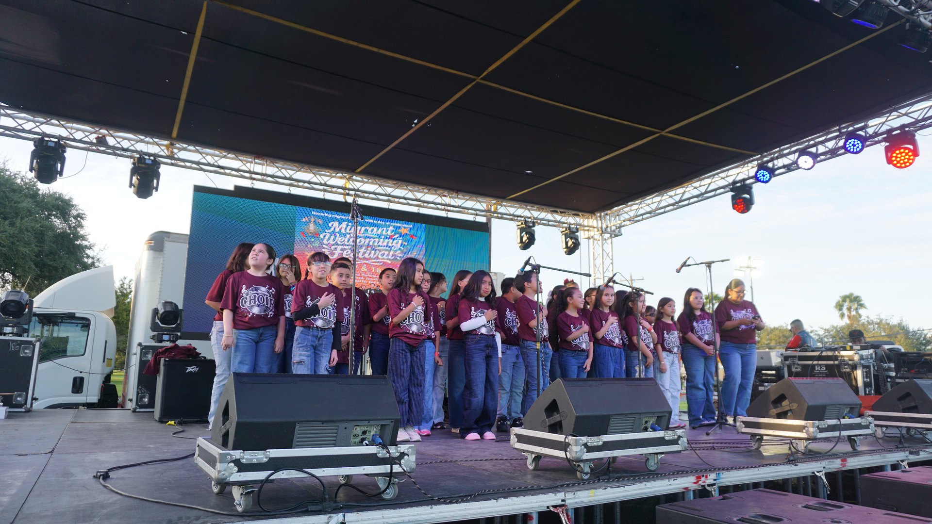 A wide view of the choir singing onstage beneath the festival lights.