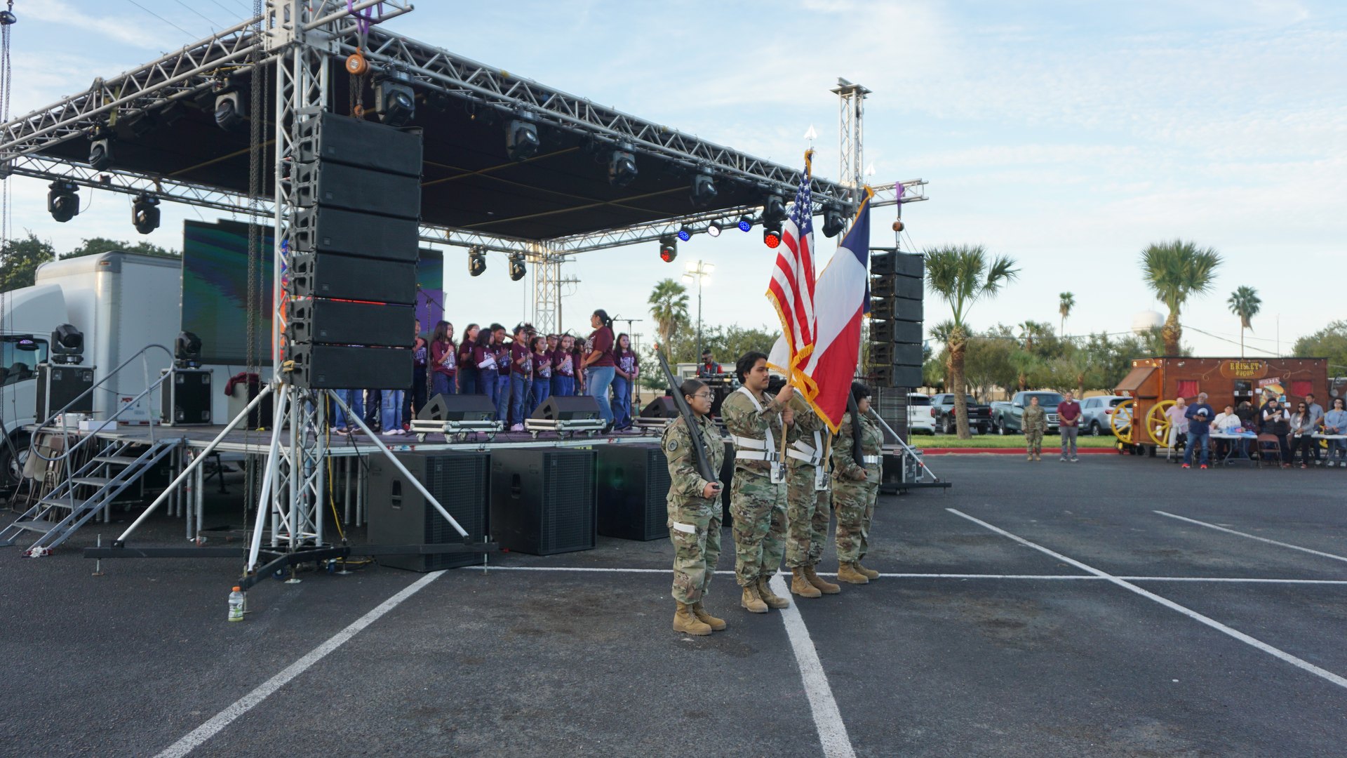 Flag bearers stand in formation beside the festival stage during the choir performance.