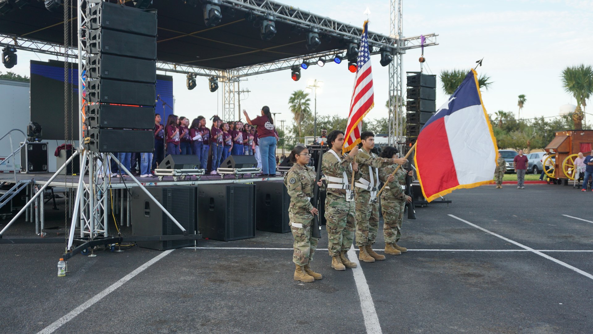 A side view of uniformed flag bearers holding the United States and Texas flags in front of the stage.