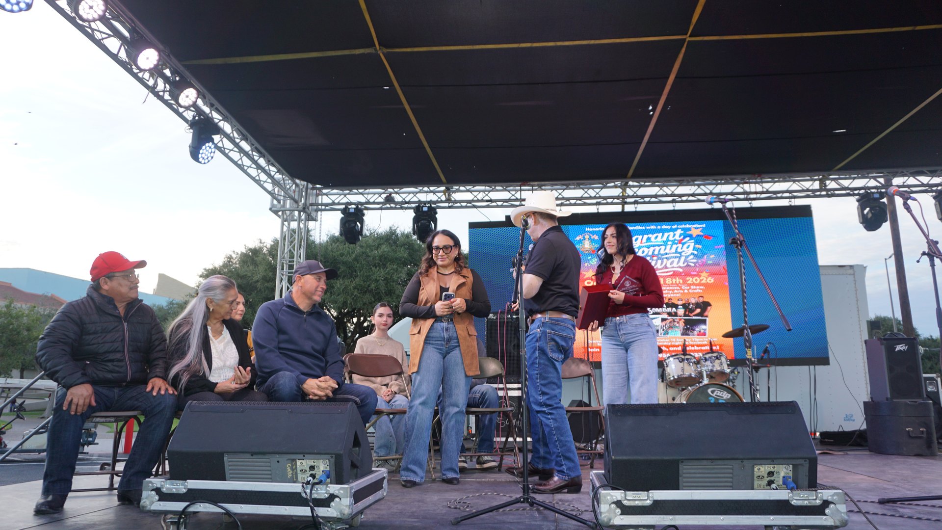 Guests stand near the microphones during the festival stage presentation.