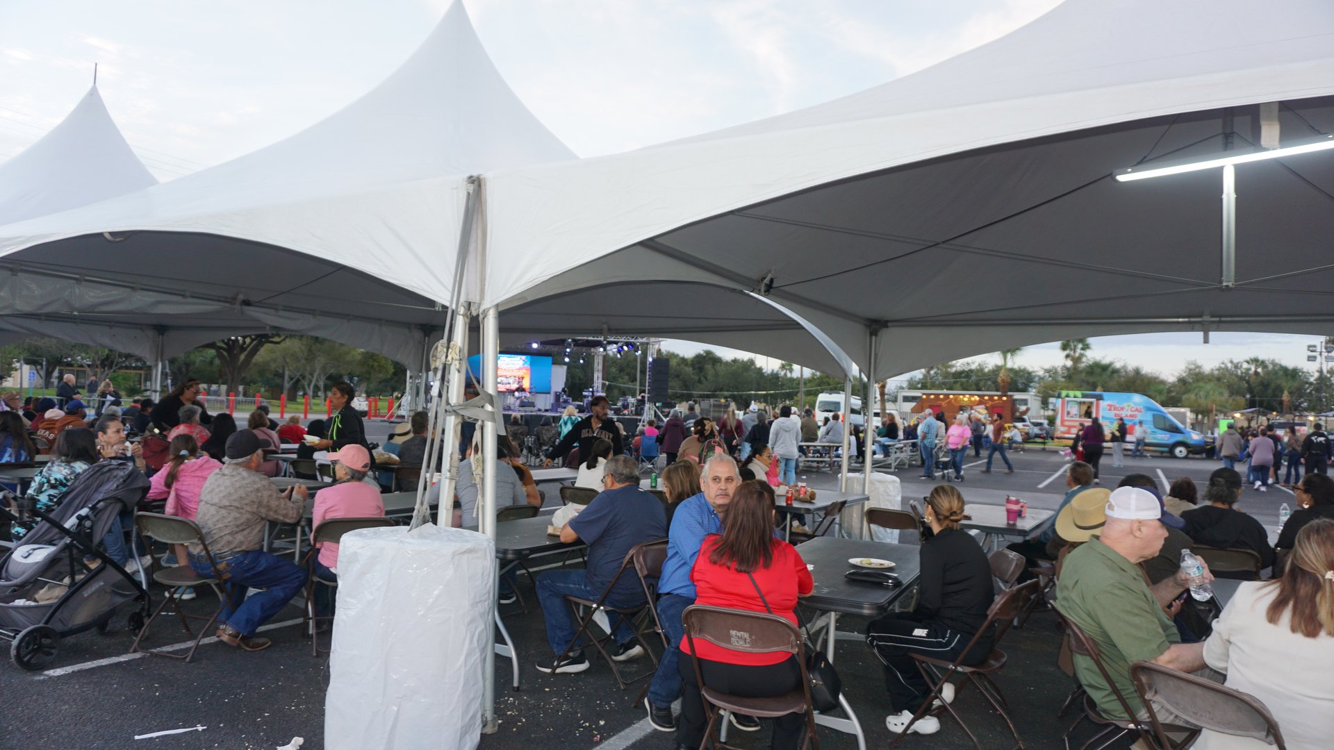 Festival guests gather at tables beneath large white tents near the outdoor stage.